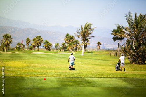 Two players walking at a golf course.