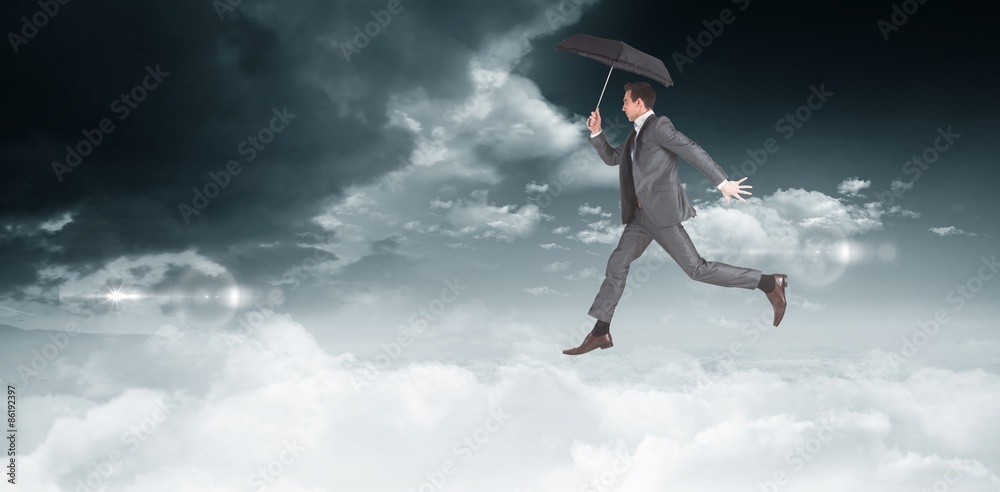 Composite image of businessman jumping holding an umbrella Composite image of businessman jumping holding an umbrella