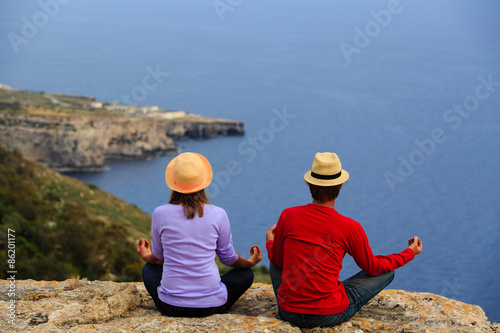 couple practicing yoga in scenic summer mountains