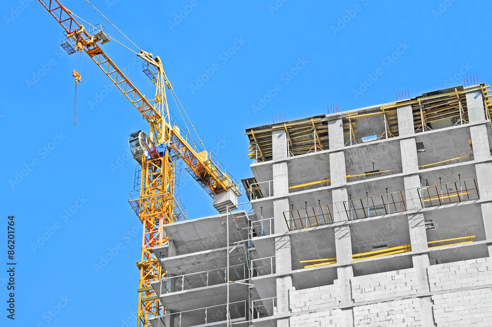 Crane and building construction site against blue sky