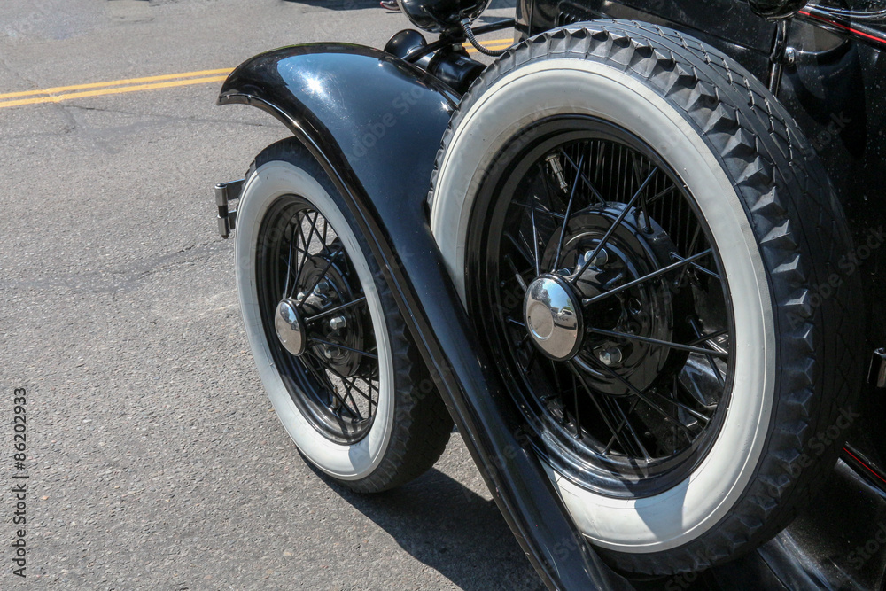 Whitewall tire and handy spare on a 1930's vintage black sedan style car, close up image