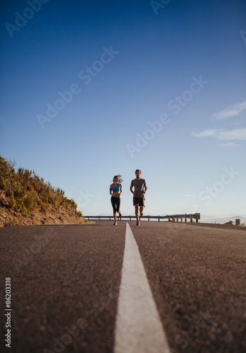 Two young people jogging on country road © Jacob Lund