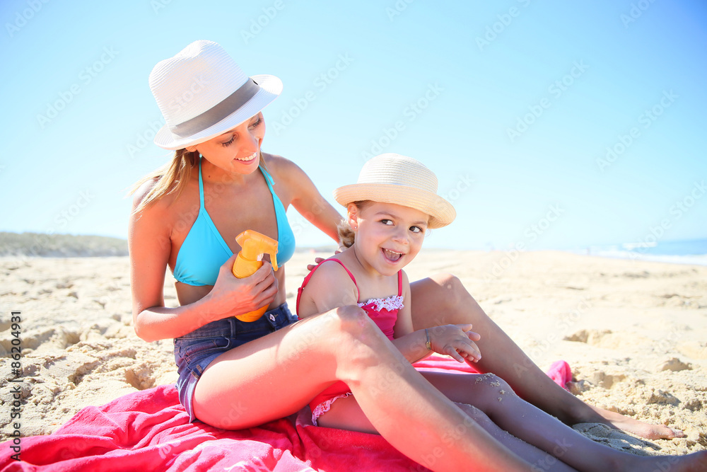 Woman applying sunscreen on daughter's body