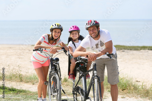 Portrait of happy family riding bikes on a sandy path