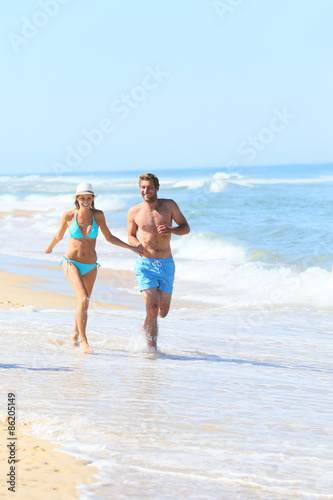 Couple having fun running on the beach © goodluz