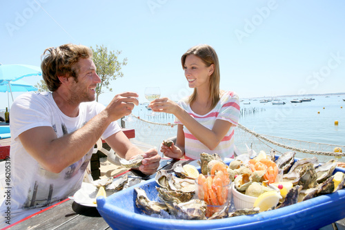 Couple in seafood restaurant tasting fresh oysters