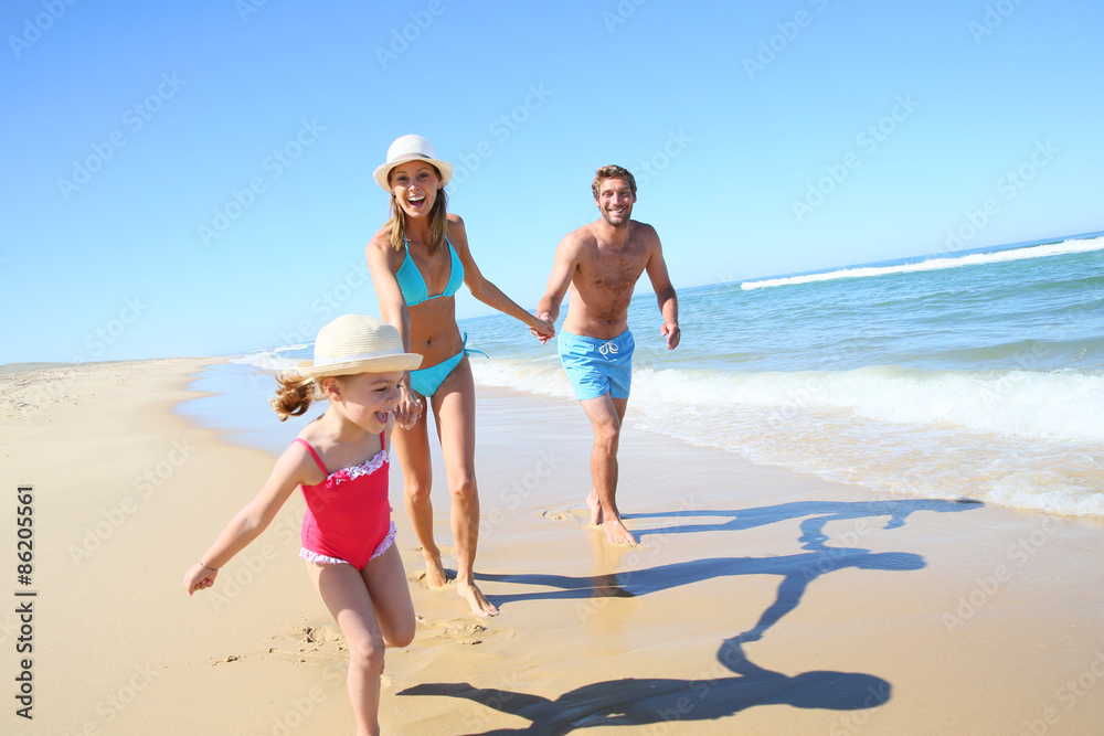 Family having fun running on a sandy beach