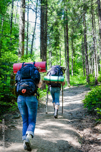 Young people hiking with backpacks. Happy travelers hikers having fun outdoors in forest.