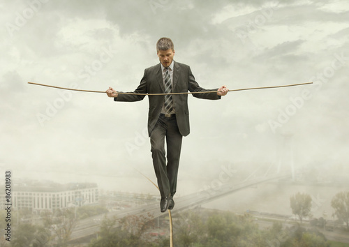 Businessman Walking on a Rope Keeping Balance with City Under-Venture Business Concept