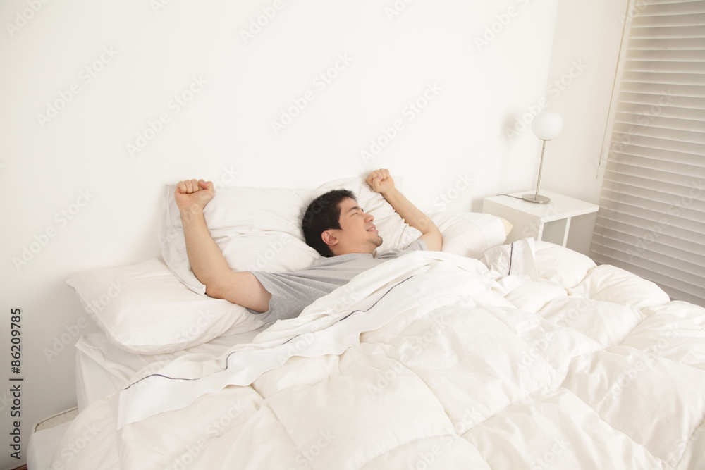 Man stretching in his bed Man stretching in his bed