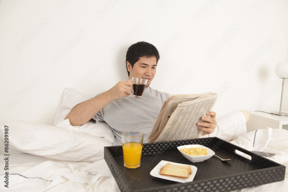 Man having a breakfast while reading the newspaper Man having a breakfast while reading the newspaper