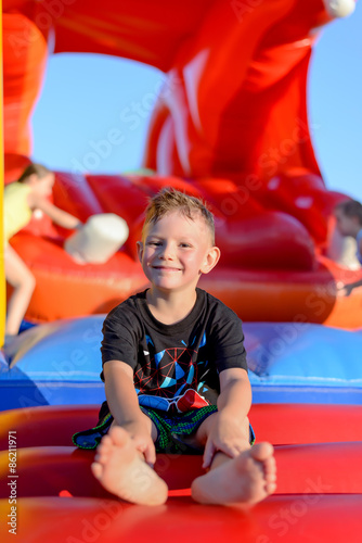 Smiling little boy sitting on a jumping castle