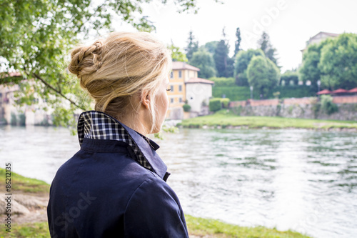 Una giovane donna riflette sulla riva di un fiume.