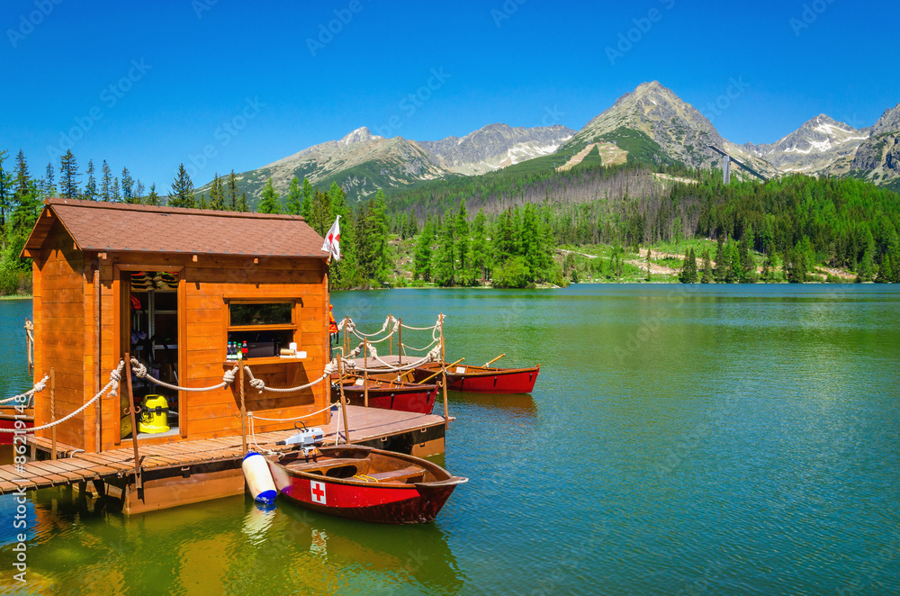Wooden hut and red boats on mountain lake