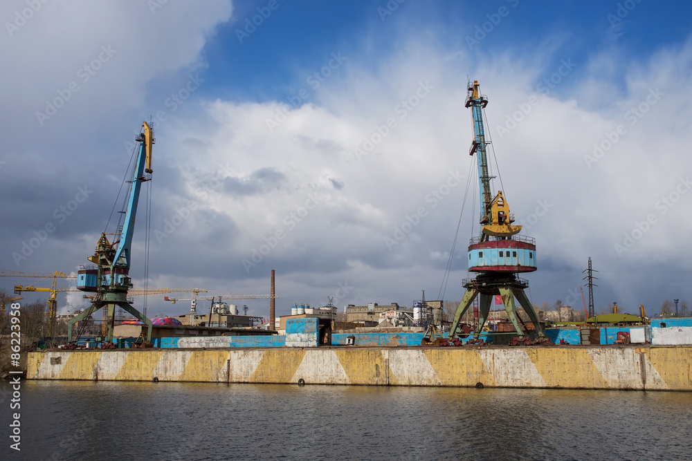 Two old crane loading cargo in the river port