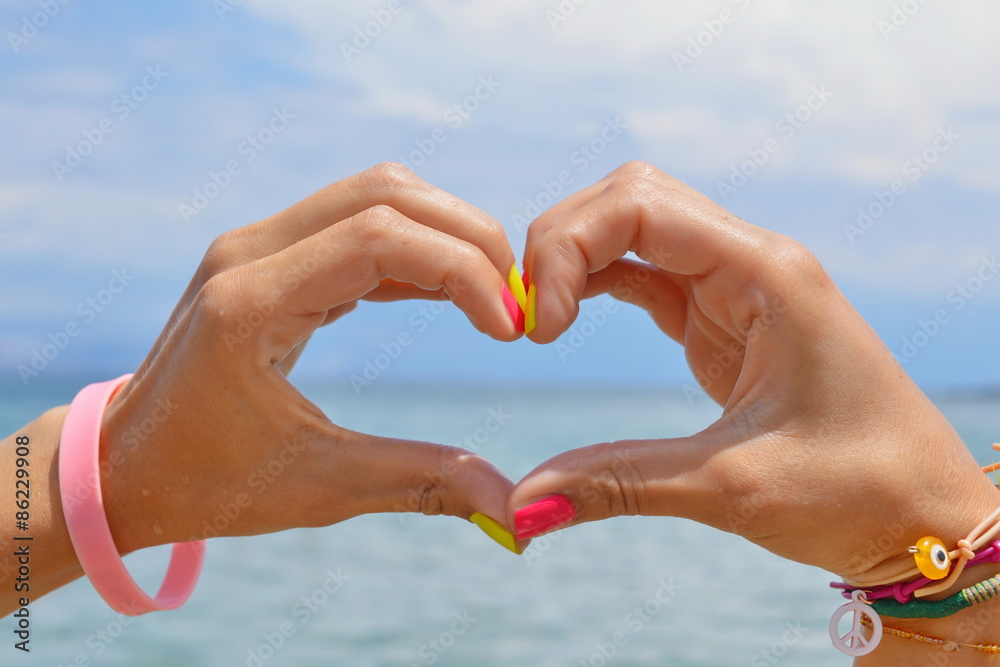 Heart shape made of hands against sea and sky Heart shape made of hands against sea and sky