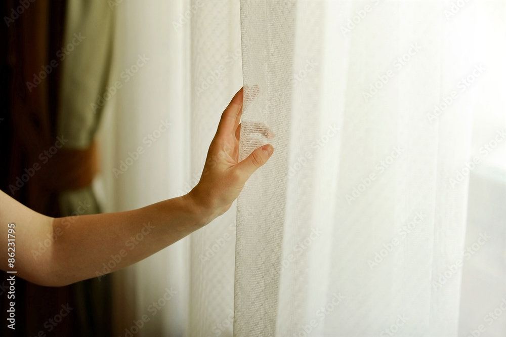 Hand pulling a window curtain