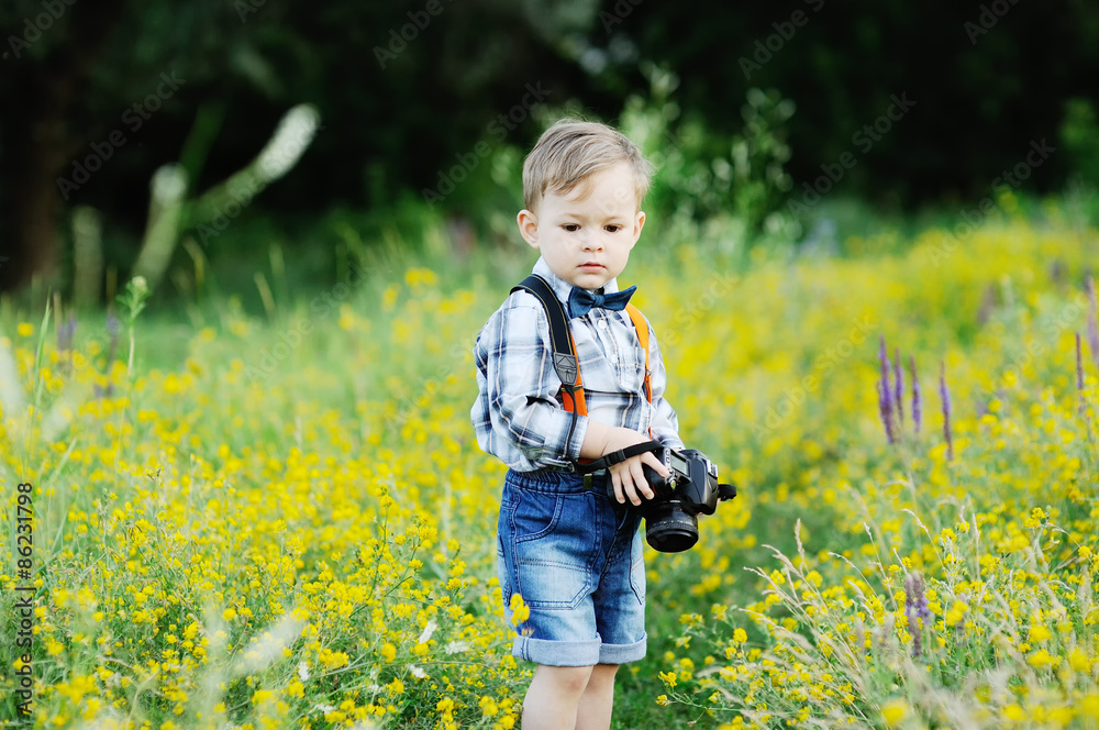 baby boy with a camera in hand against the background of a flowe baby boy with a camera in hand against the background of a flowe