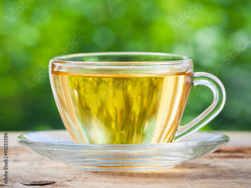 Tea cup on wooden table. Green background.