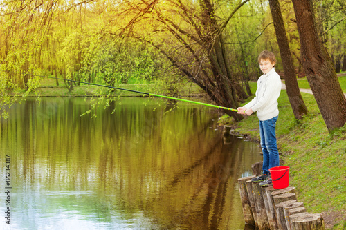 Boy standing and fishing near the pond