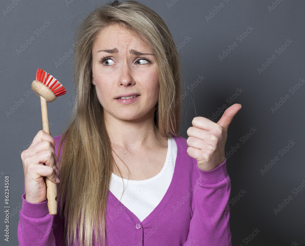 scared young blond woman displaying dish brush for question about washing dishes scared young blond woman displaying dish brush for question about washing dishes