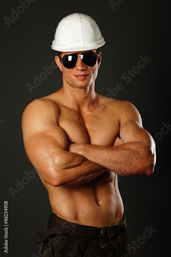 Portrai of builder in sunglasses and with helmet on gray backgroung