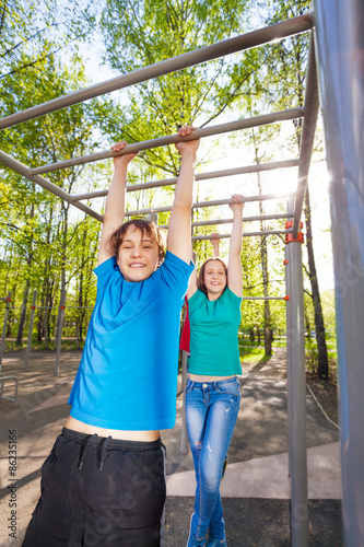 Boy and girl hanging on the brachiating bar photo