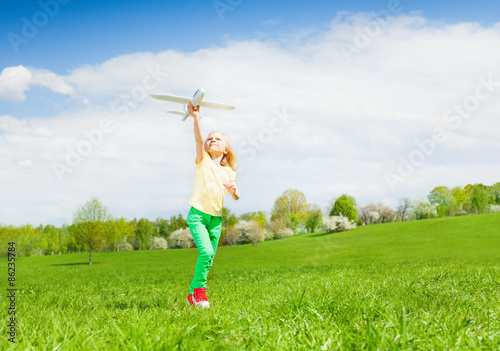 Blond girl holding airplane toy during running