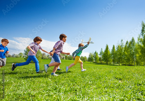 Boy with airplane and following him children run