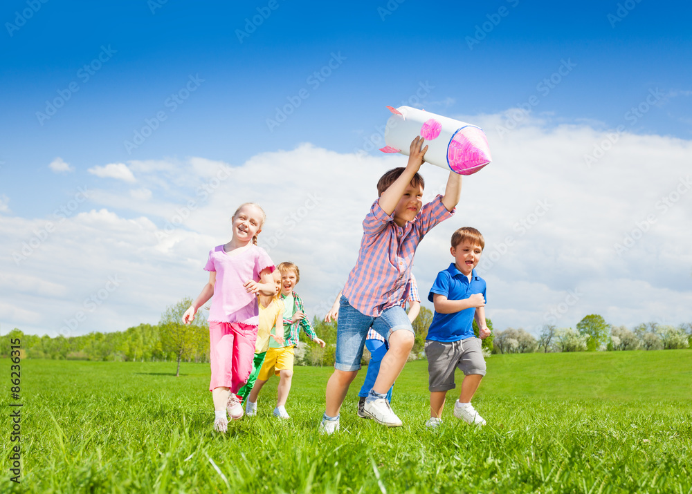 Obraz premium Happy boy holding rocket carton toy and kids run