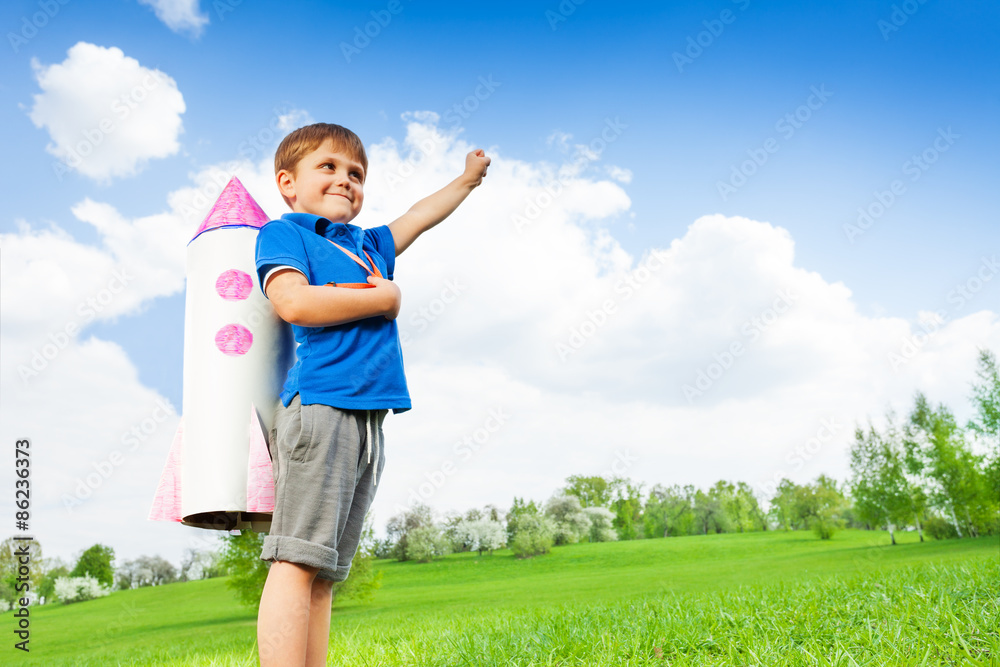 Boy wears paper rocket toy and holds arm up Boy wears paper rocket toy and holds arm up