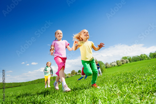 Happy girls and other kids running in green field