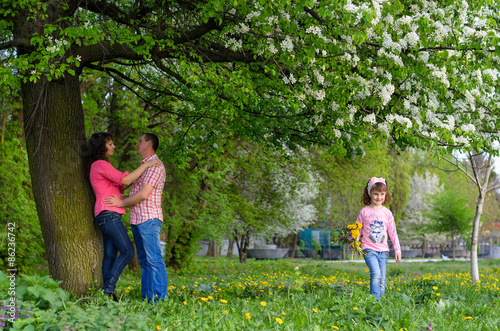 a girl collects the field flowers in a bouquet sits near parents © banzaygelo