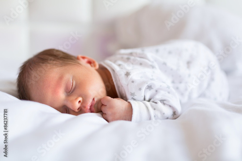 Newborn baby boy sleeping in bed