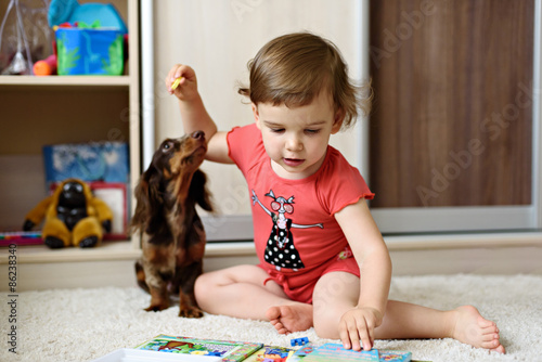 little girl with dolittle girl with a dog breed dachshund play at home photo