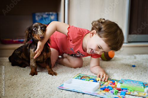 little girl with dolittle girl with a dog breed dachshund play at home photo