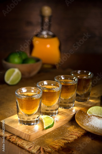 Gold Tequila shot glasses and bottle served in a group artistic lighting