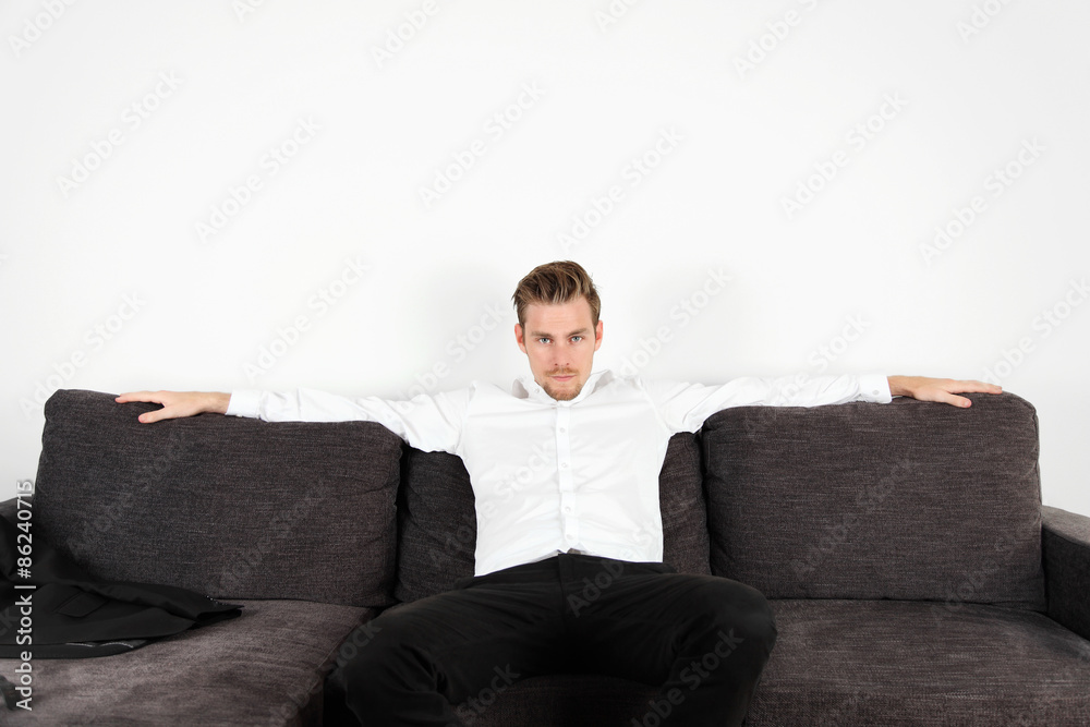 Man in his 20s sitting down in a sofa indoors wearing a shirt Man in his 20s sitting down in a sofa indoors wearing a shirt