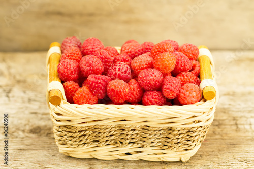 ripe raspberries in the basket on wooden