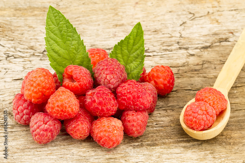 ripe raspberries with mint leaves closeup on wooden background, top view