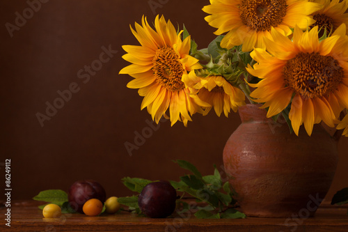 Bouquet of sunflowers and ripe cherry plums with copy space.  Fragment.  Focus on the left flower