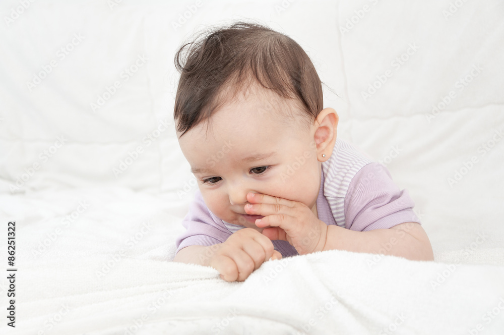 Smiling cute baby girl lying on stomach in bed. High key Smiling cute baby girl lying on stomach in bed. High key
