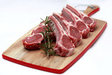 Raw lamb cutlets with rosemary on chopping board white background