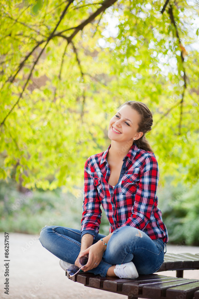 Young pretty woman in the park sitting on the bench Young pretty woman in the park sitting on the bench