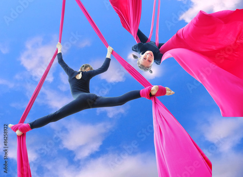 cheerful children training on aerial silks in the sky
