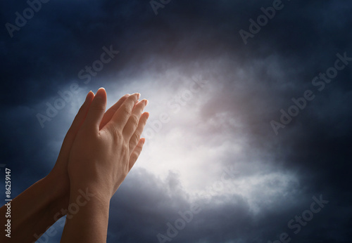 Hand reaching for the sky with dark stormy clouds