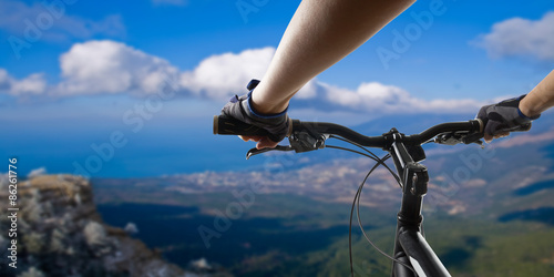 Hands in gloves holding handlebar of a bicycle. Mountain Bike cyclist riding single track. Healthy lifestyle active athlete doing sport
