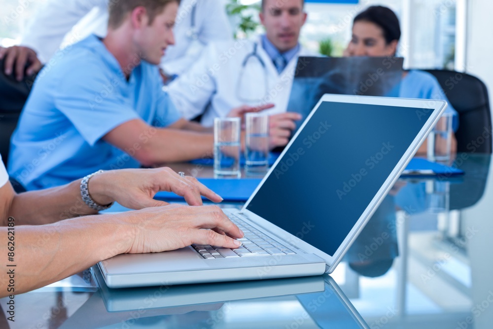 Doctor typing on keyboard with her team behind Doctor typing on keyboard with her team behind