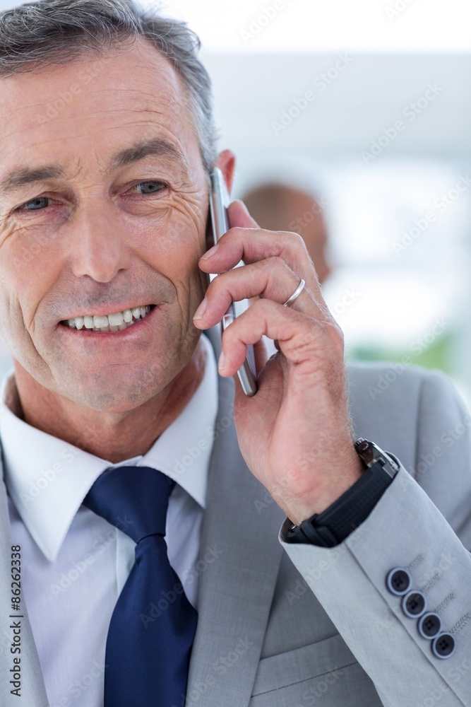 businessman using her phone with two colleague behind him businessman using her phone with two colleague behind him