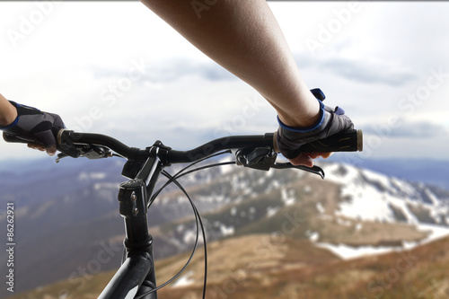 Hands in gloves holding handlebar of a bicycle. Mountain Bike cyclist riding single track. Healthy lifestyle active athlete doing sport